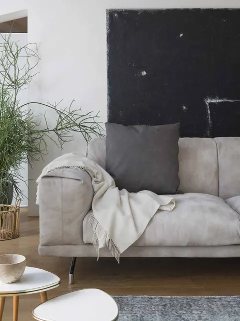 Divano Dall'Agnese grigio chiaro con plaid in maglia e tavolino laterale bianco, ispirazione per un divano moderno in tessuto