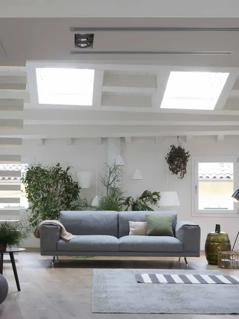 Divano Dall'Agnese grigio in un loft luminoso con lucernari, divano italiano moderno per appartamento