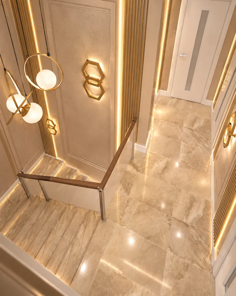 Staircase seen from the upper hall: stone-look steps, wood handrail on glass and brass hexagon wall lights