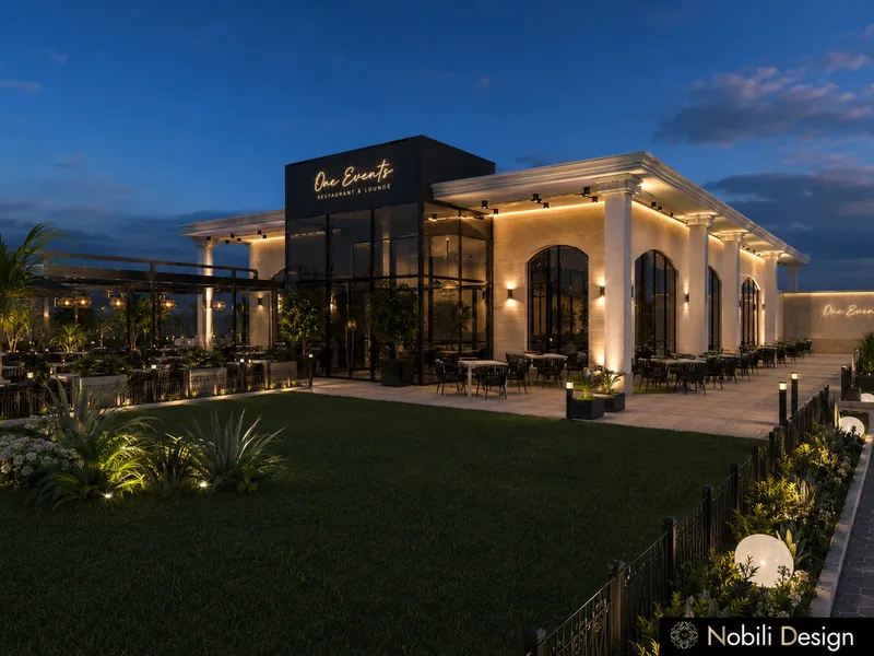 Event venue facade with arched windows, columned porch, lit terrace tables and a planted lawn at night