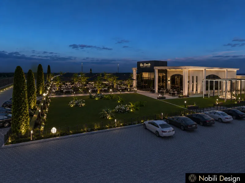Event venue grounds with lawn, cypress hedges, lit terrace and car park in front of the reception hall at dusk